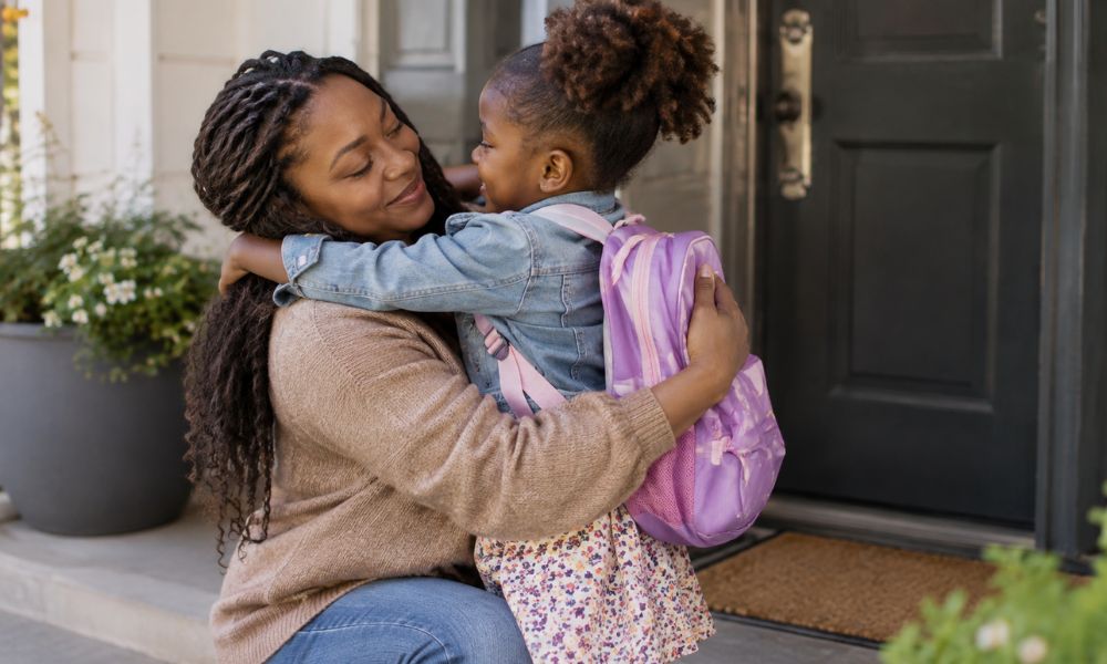 A Black mother kneeling to embrace her child at the front door during a Co-parenting as a Black parent handover